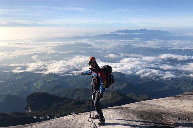 A climber on Mount Kinabalu's granite slabs looking out over a sea of cloud towards the Crocker Range