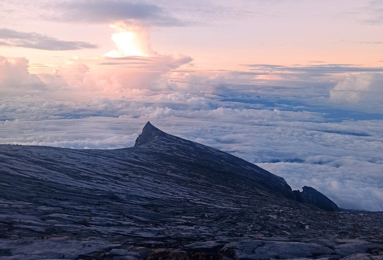 Mount Kinabalu's summit massif in silhouette above a sea of cloud at first light