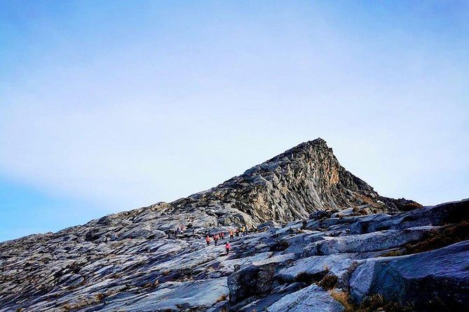 The summit pyramid of Low's Peak above the bare granite of the plateau, with a line of climbers on the trail below it