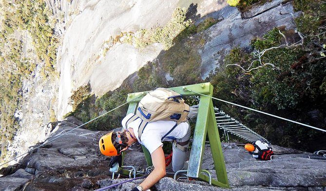 A climber on the fixed ladder of the Walk The Torq via ferrata, high on Mount Kinabalu's granite